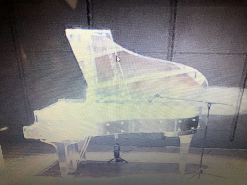 幻想的に光り輝く透明なグランドピアノ(クリスタルピアノ)がステージに置かれている様子